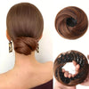 A close-up of a brown synthetic hair bun styled in a low chignon with black elastic clips.