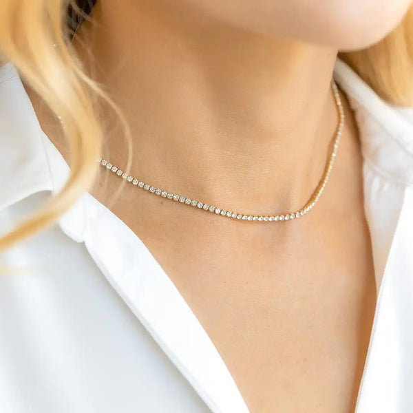 A close-up of a delicate, iced out cubic zirconia choker necklace worn around the neck.