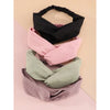 Ein Set aus vier weichen Stoff-Haarbändern in Schwarz, Pink und Salbeigrün auf hellem Hintergrund.