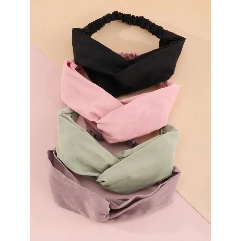 Ein Set aus vier weichen Stoff-Haarbändern in Schwarz, Pink und Salbeigrün auf hellem Hintergrund.