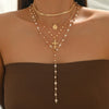 A close-up of a layered gold necklace featuring a pearl cross pendant and multiple strands for daily wear.