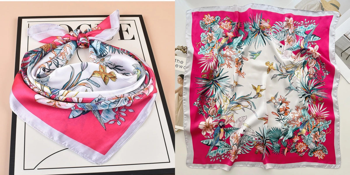 A pink and white floral print silk scarf tied in a bow, displayed on a black surface.