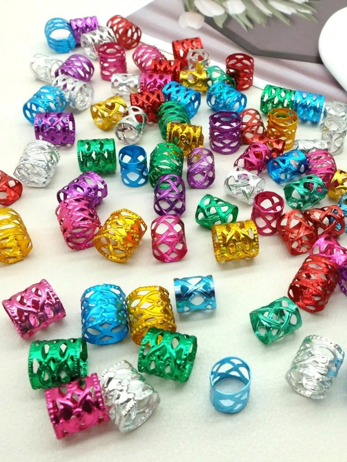 A collection of multicolor dreadlock hair rings in various shades including pink, purple, green, yellow, and silver.