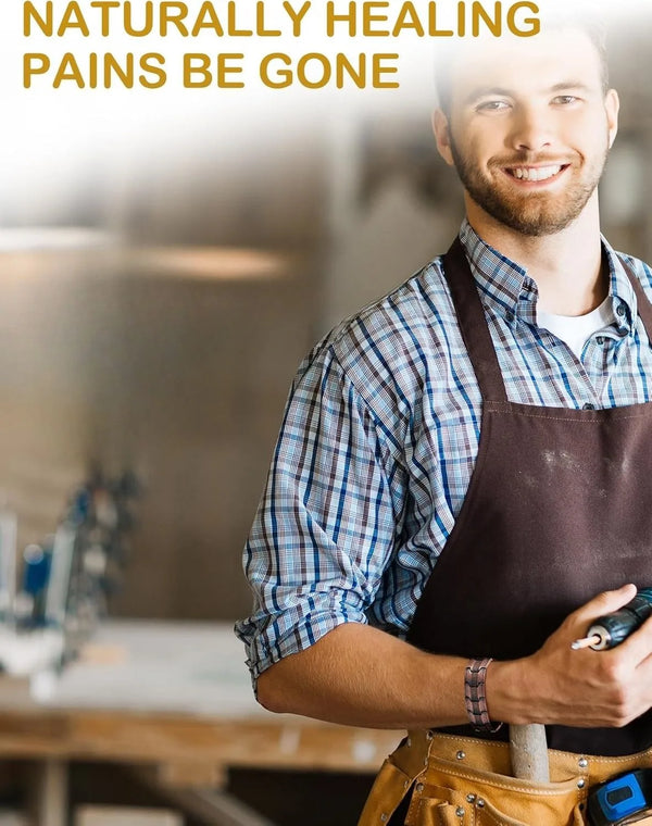 A smiling man wearing a denim shirt and apron holds a copper magnetic bracelet.