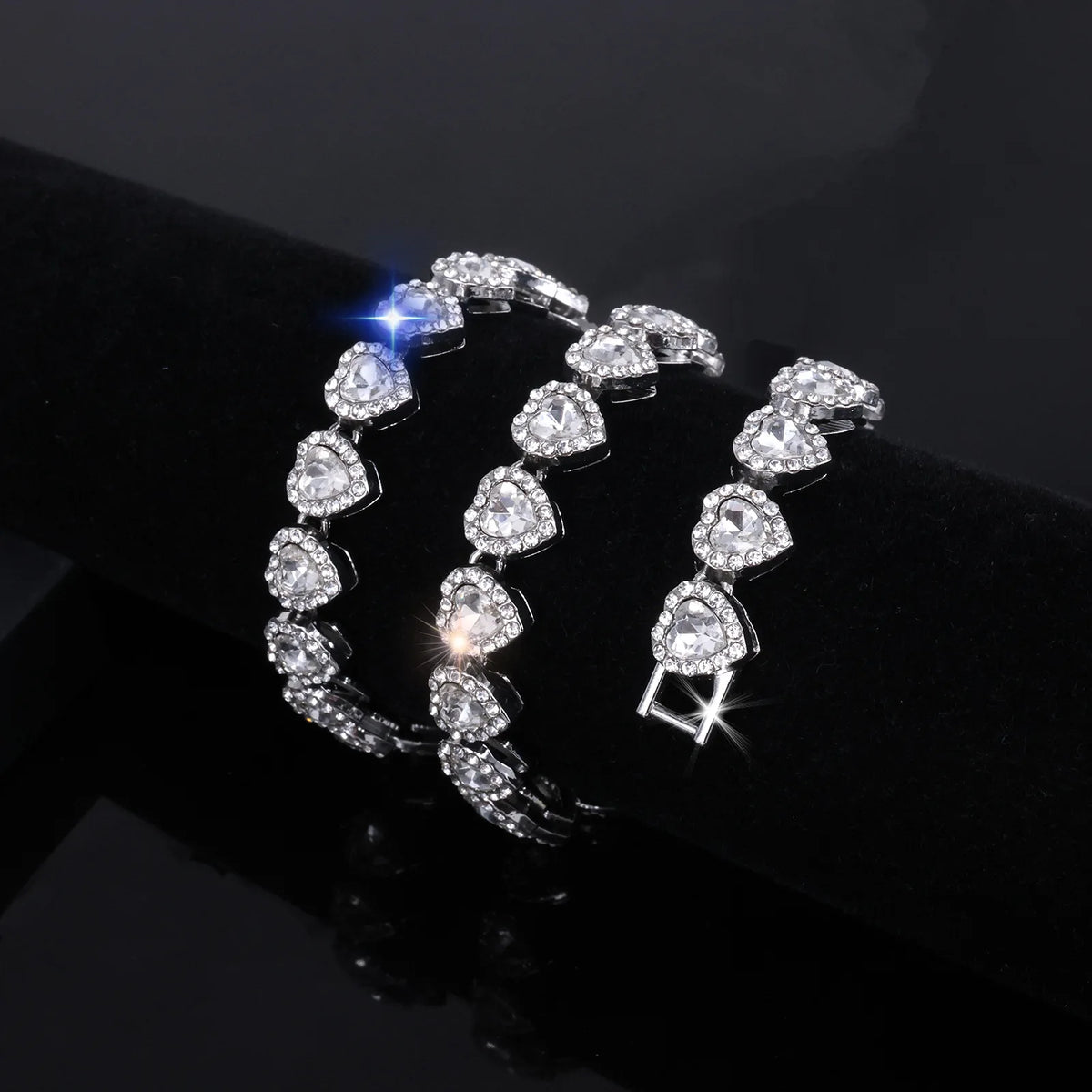 A set of sparkling heart rhinestone necklaces and bracelets displayed on a black surface.