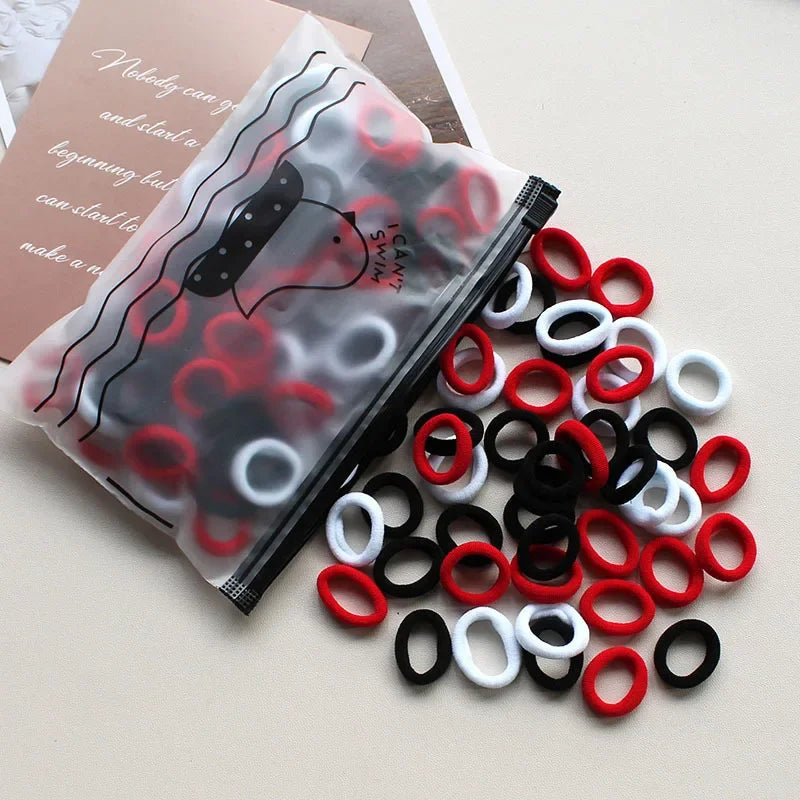 A collection of red, black, and white elastic hair bands are displayed on a light surface.