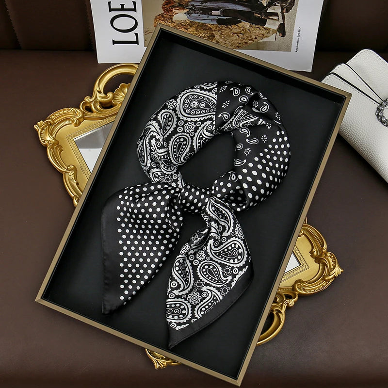A black silk scarf with white polka dots tied in a knot displayed in a gold-framed picture.