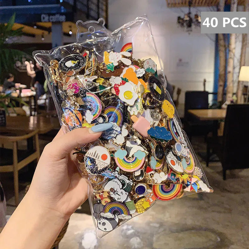 A hand holds a clear plastic bag filled with 40 assorted enamel badge pins and decorative brooches.