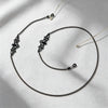 A delicate black metal link strap for glasses and sunglasses is displayed on a light gray fabric.