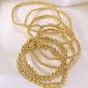 A set of minimalist round beaded bracelets in gold color arranged on a white background.