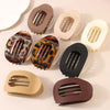 A collection of matte oval hair claw clips in various shades including brown, beige, and black leopard print patterns.