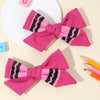 A set of pink and black striped fabric bows used as hair clips, displayed on a light background.