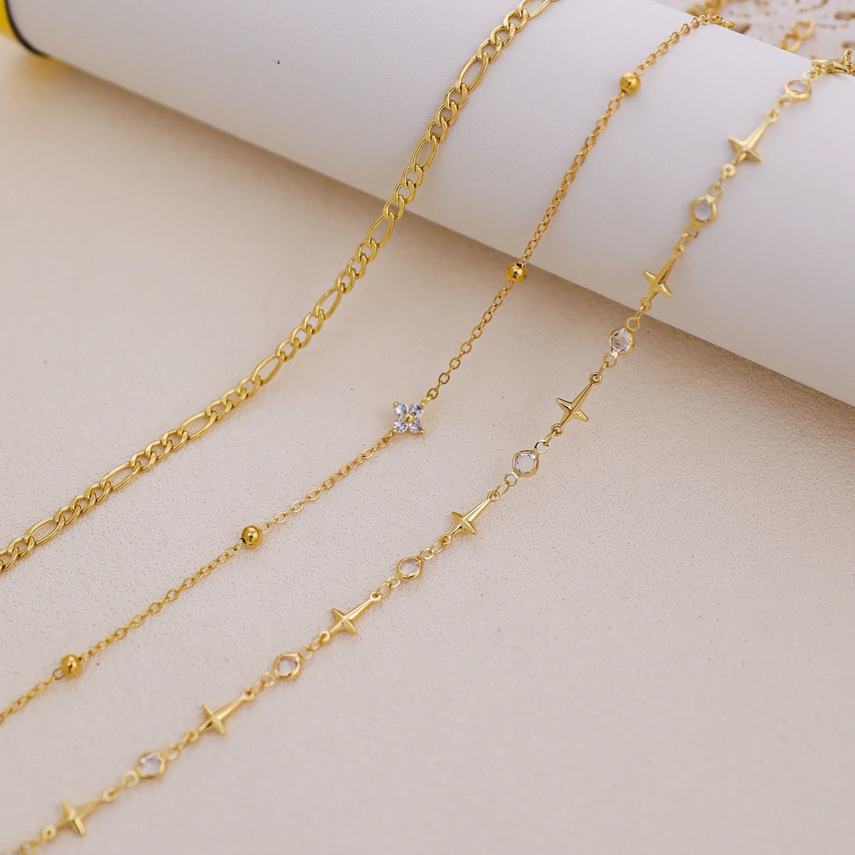 Gold-toned handmade crystal cross anklets set displayed on a light background.