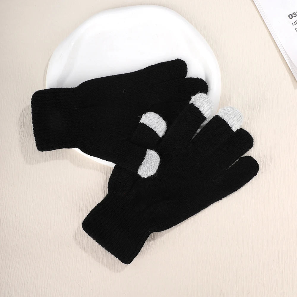 A pair of black knit touch screen gloves with white accents resting on a white plate.