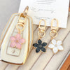 Llavero floral tono dorado con flores rosas y blancas en un dije rectangular transparente