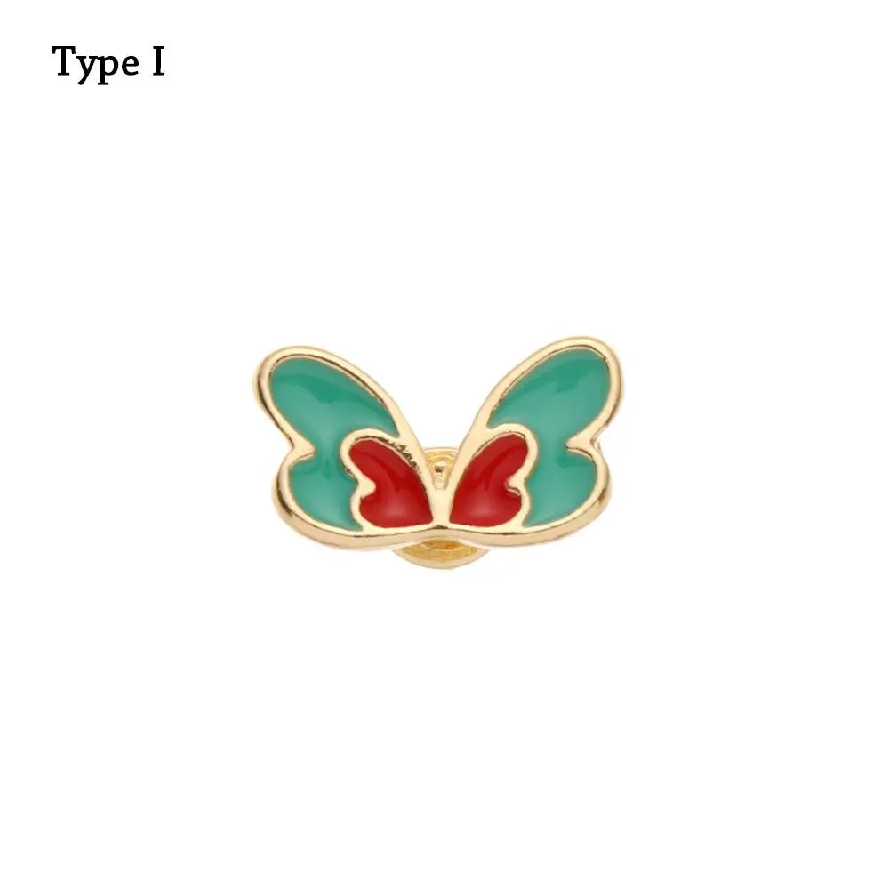 Adorno de pulsera de metal con forma de mariposa y detalles en esmalte verde y rojo.