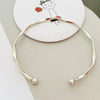 Silver twisted wave cuff bracelet worn on a white background with a hand-drawn illustration.