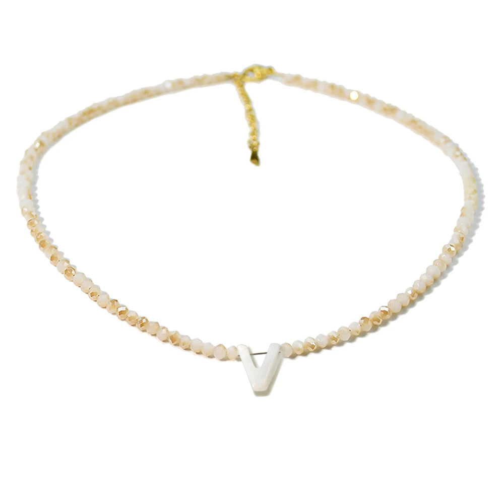 A delicate mother of pearl initial necklace featuring crystal accents on a gold-toned chain.