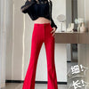A woman models high-waist flare skinny red pants and a black top in a studio setting.