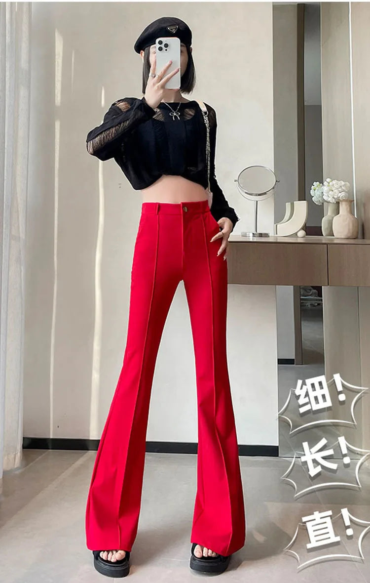 A woman models high-waist flare skinny red pants and a black top in a studio setting.
