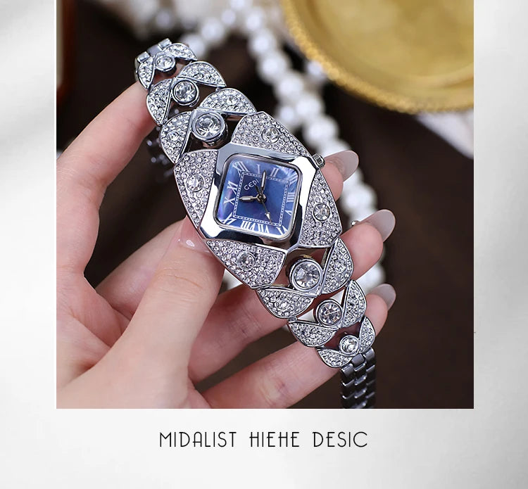 A hand holds a diamond-inlaid quartz wristwatch with intricate silver detailing and a blue dial.