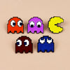 A set of retro Pac-Man enamel pins in orange, purple, yellow, and blue.