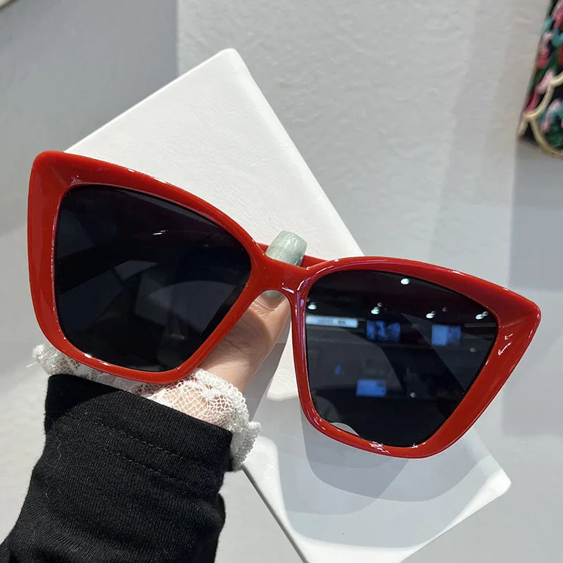 A pair of bright orange retro cat eye sunglasses resting on a white surface.