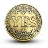 A round antique bronze coin with the word YES embossed in the center surrounded by decorative scrollwork.