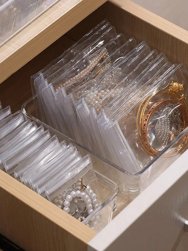 Une boîte en plastique transparent remplie de paquets de bijoux et de bagues auto-scellants.
