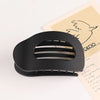 A black flat circular hair clip is shown next to a piece of paper with a line drawing of a bird.