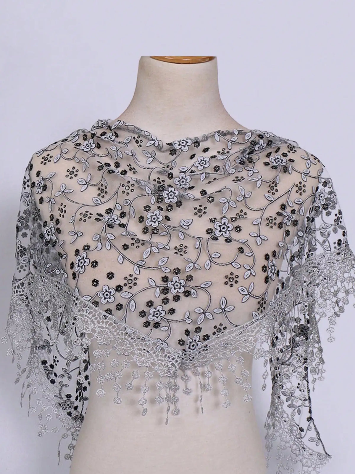 A sheer black and gray floral lace scarf draped over a mannequin's neck.