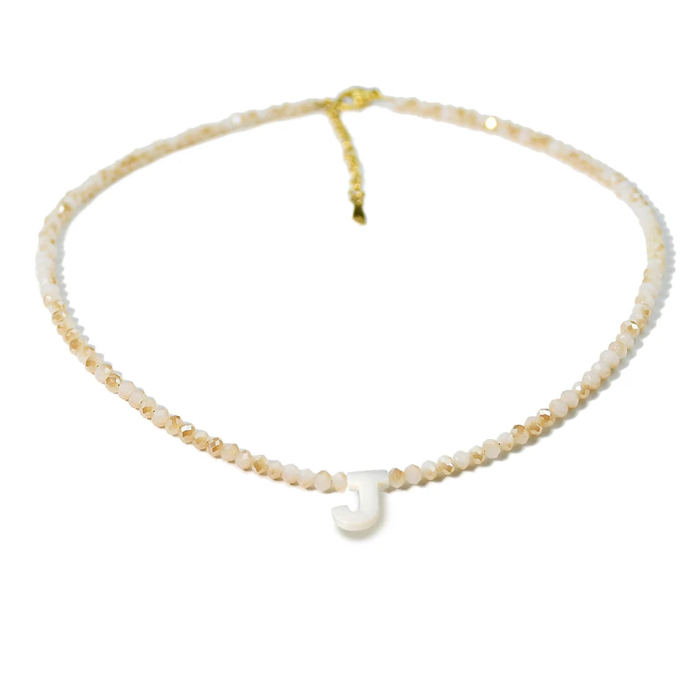 A delicate necklace featuring mother of pearl beads and crystal accents, forming the initial J.