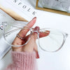 A hand holds clear, large square anti-blue light spectacles against a white background.