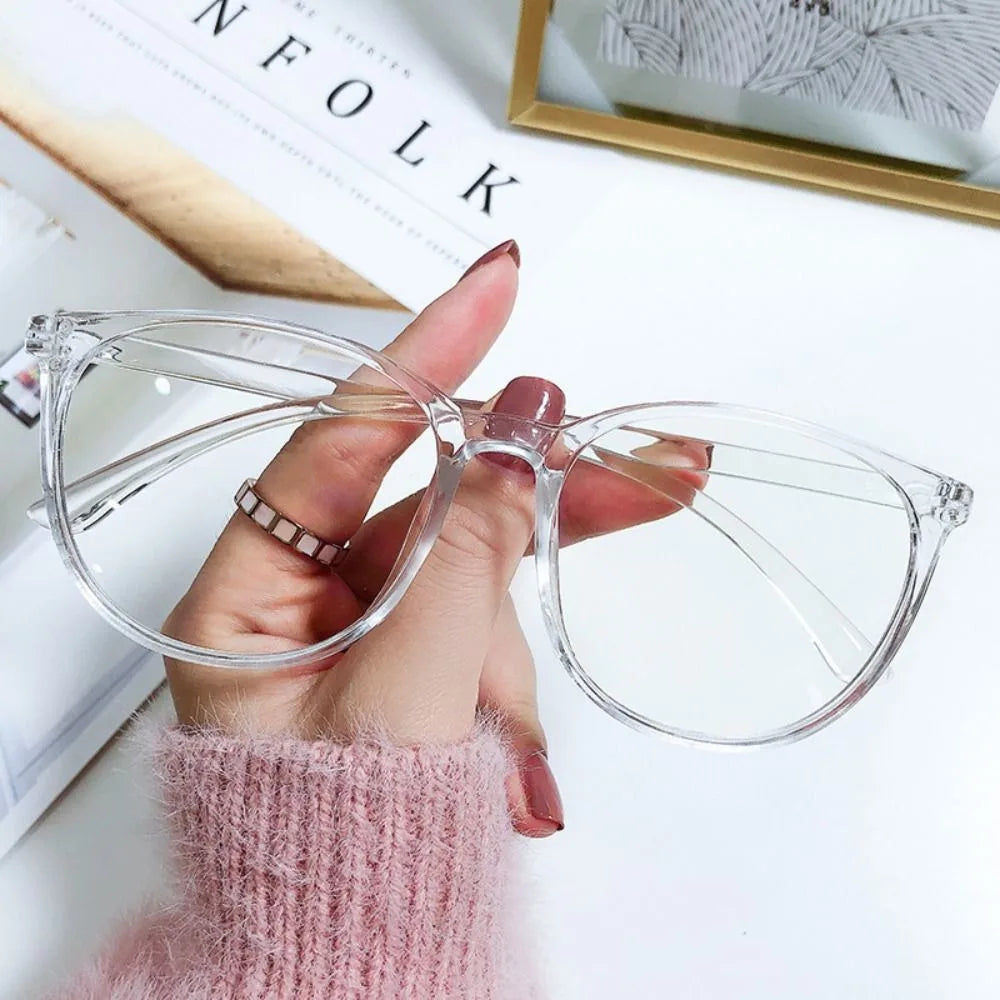 A hand holds clear, large square anti-blue light spectacles against a white background.