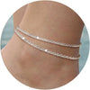 Gold plated glitter layered anklets worn on a person's ankle.