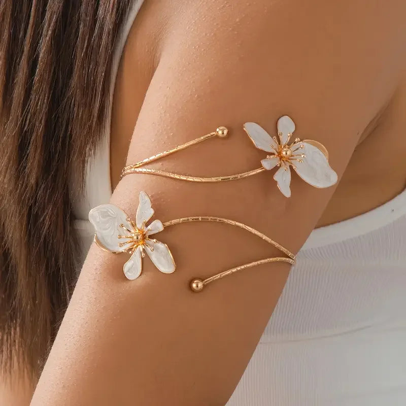 Gold floral open cuff armlet jewelry worn on a person's arm.