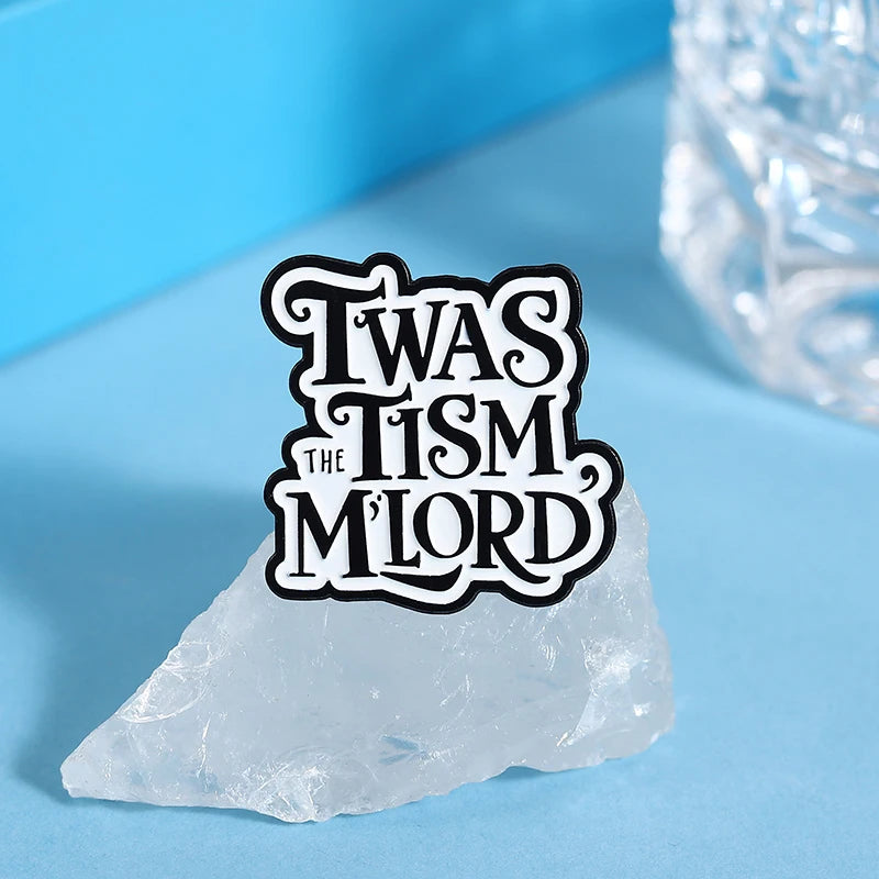 An enamel lapel pin featuring the text TWAS THE MILORD on a clear ice-like stone.
