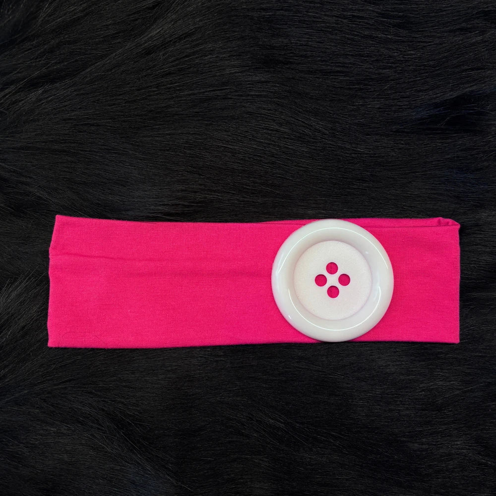 Pink stretch hairband with a white circular dot accent on a black fur background