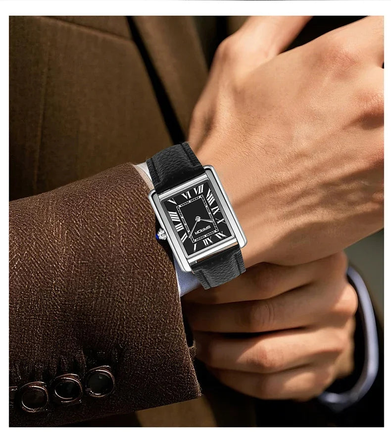 Nahaufnahme einer Person mit einer silbernen Uhr und schwarzem Lederarmband, neben einem braunen Sakkojacke.