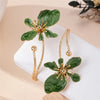 Gold floral open cuff armlet jewelry featuring green leaves on a white background.