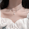 Gros plan d'un collier de perles minimaliste porté autour du cou sur un fond rose doux.
