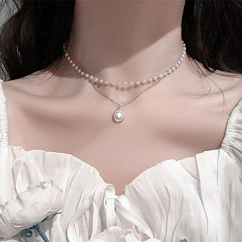 Gros plan d'un collier de perles minimaliste porté autour du cou sur un fond rose doux.
