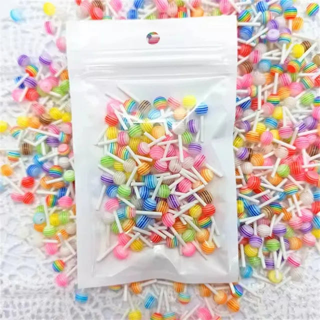 A small plastic bag filled with colorful resin nail art charms and glitter scattered around it.