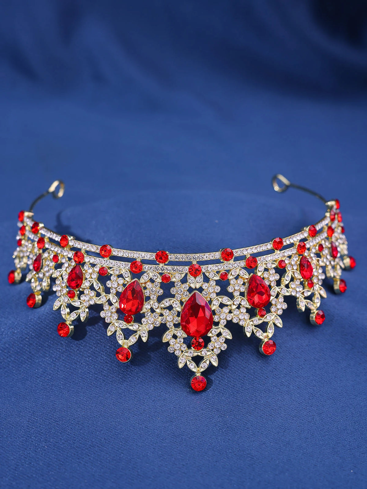 An elegant crystal rhinestone tiara and headband set featuring red and clear stones against a blue background.