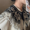 Gros plan d'une chemise vintage avec un col en dentelle noire amovible et des détails de franges argentées.