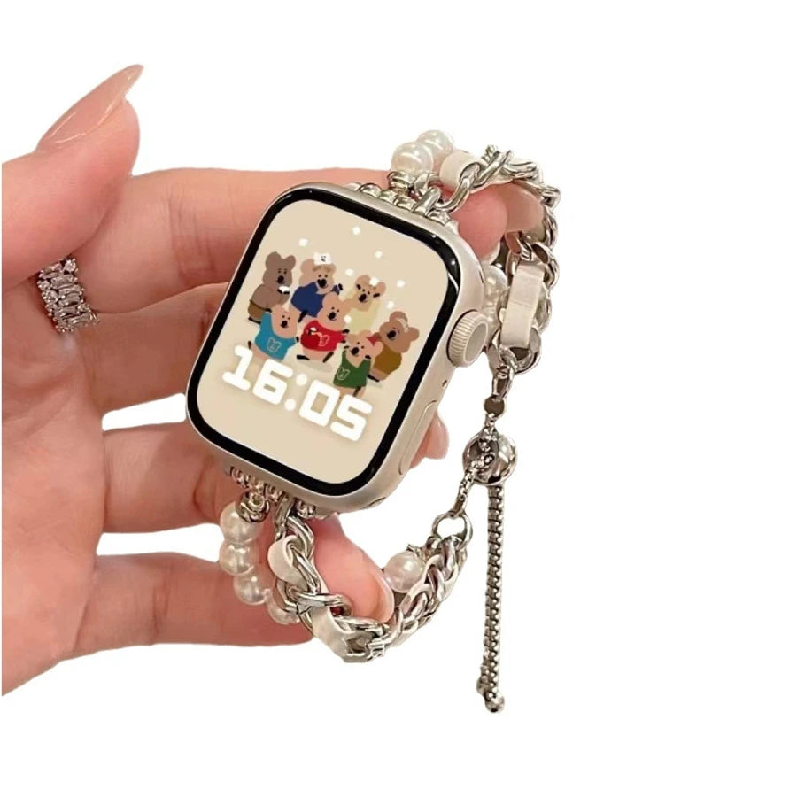 A hand holds a digital watch with a square face displaying 16:05 and is attached to a beaded watch strap.