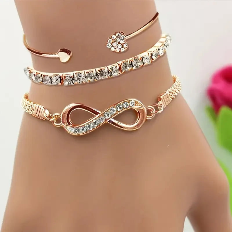 A set of three vintage crystal heart charm bracelets worn on a wrist.