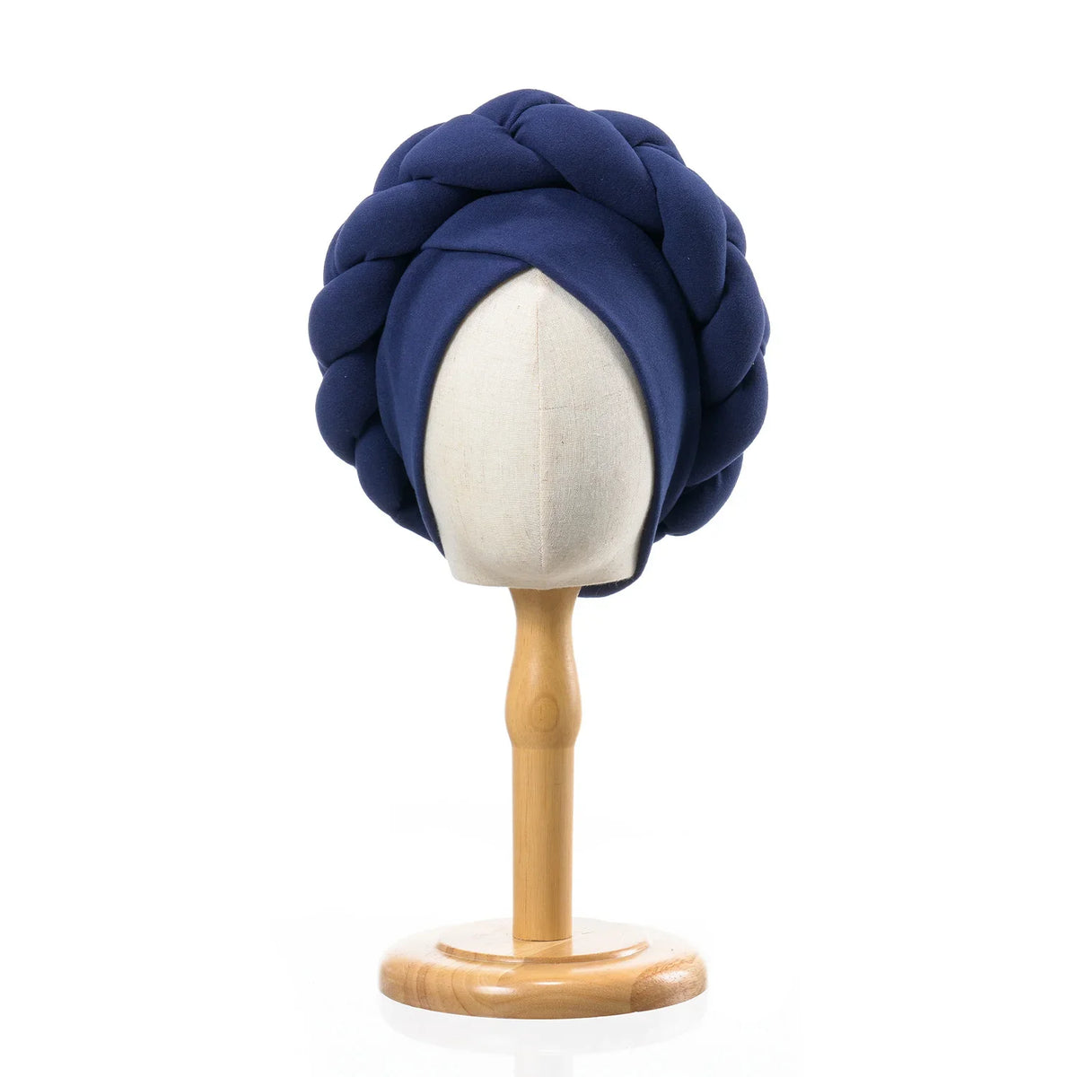 A navy blue braided turban cap displayed on a wooden mannequin stand.