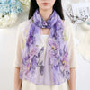 Un châle floral de soie violet drapé autour du cou, porté par une femme sur un fond clair.