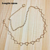 A delicate gold-tone chain necklace featuring heart-shaped charms, displayed on a light wooden surface.